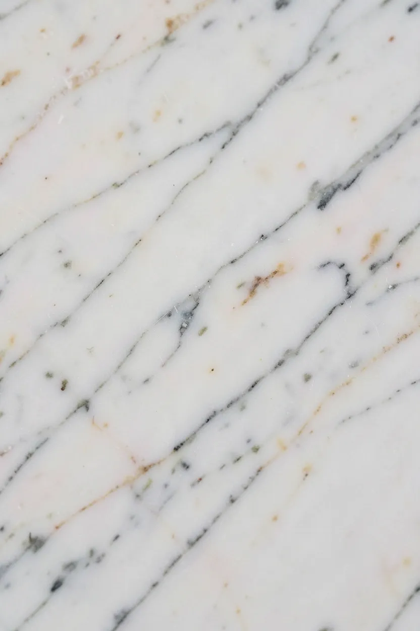 Honed Carrara marble bathroom countertop with visible gray veining and matte surface texture in a minimal wabi-sabi bathroom