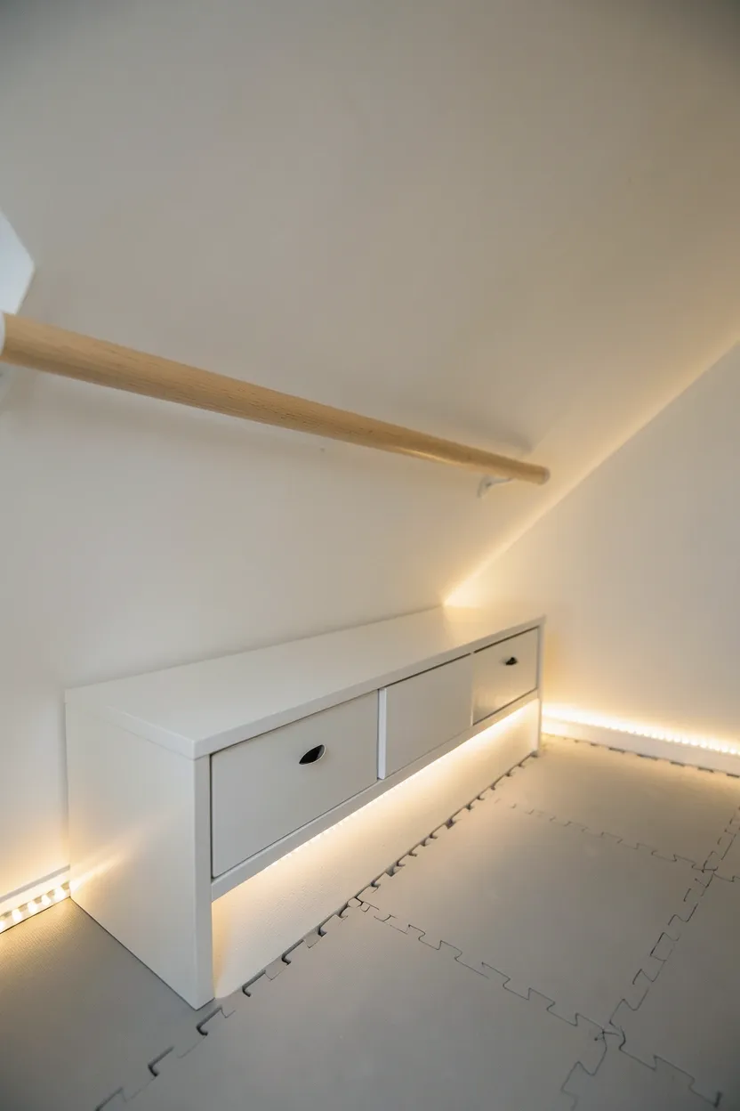 Under-stairs mini home gym with foam tiles, wall-mounted barre, and built-in storage shelves for workout equipment