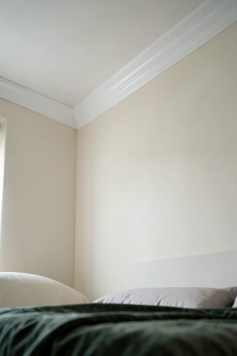Elegant white crown molding at ceiling line with warm cove lighting in a polished modern luxury bedroom